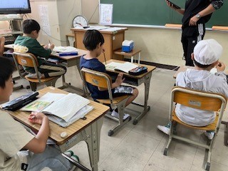 児童4人が机に座り教科書を読んでいる