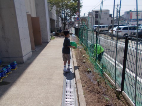 児童が畑にジョウロで水をやっている